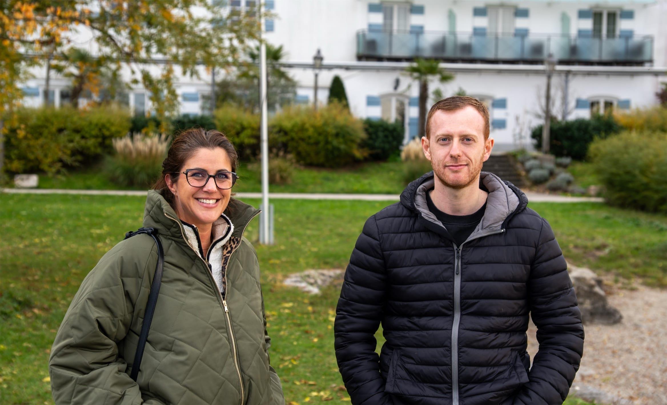 Zwei Teammitglieder stehen beim internen Team-Retreat im Garten der Unterkunft und lächeln in die Kamera